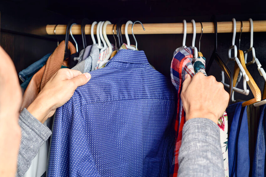 Man looking through clothes in closet