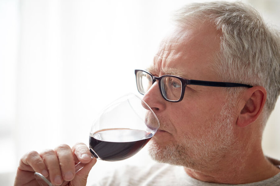 Older male drinking wine