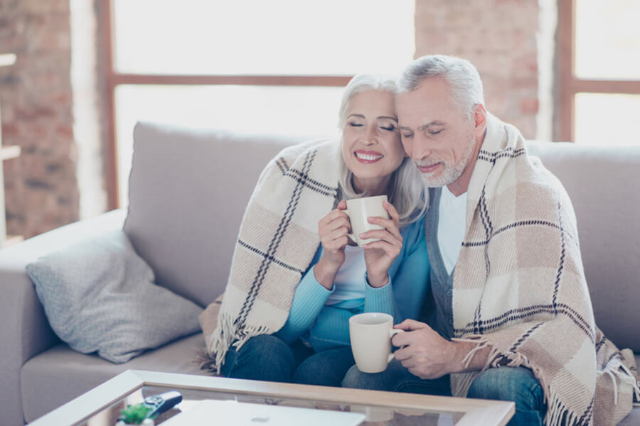 Older Couple sitting on couch drinking coffee