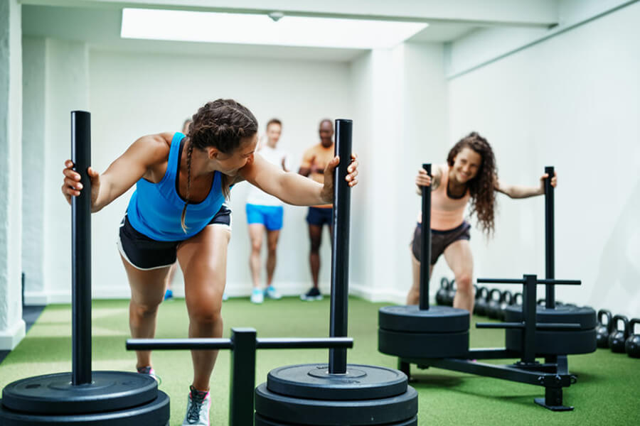 Two women pushing weights in gym