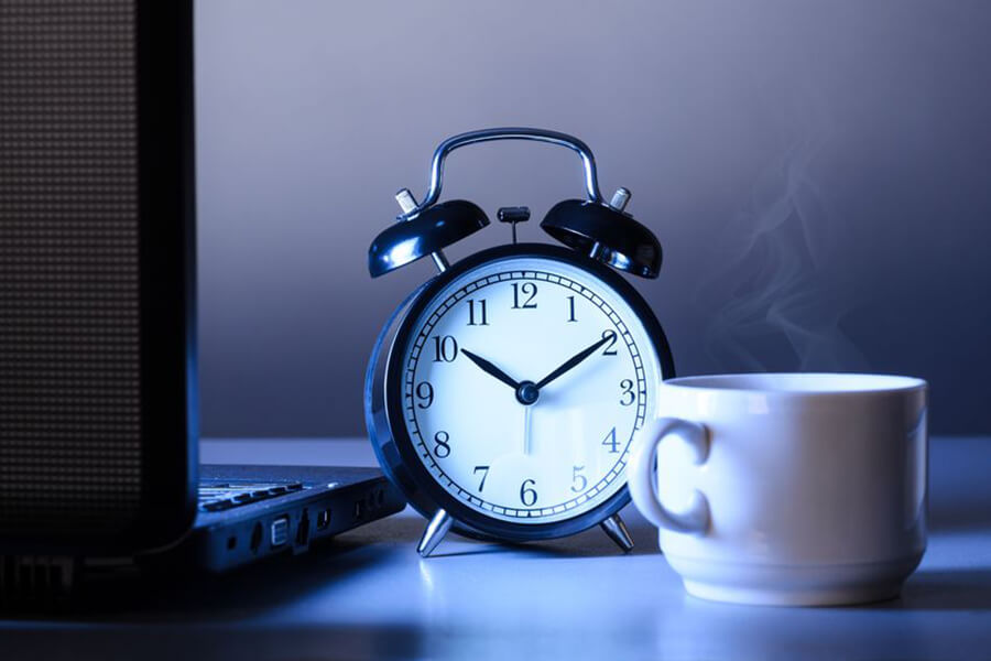 A clock cup of coffee and laptop