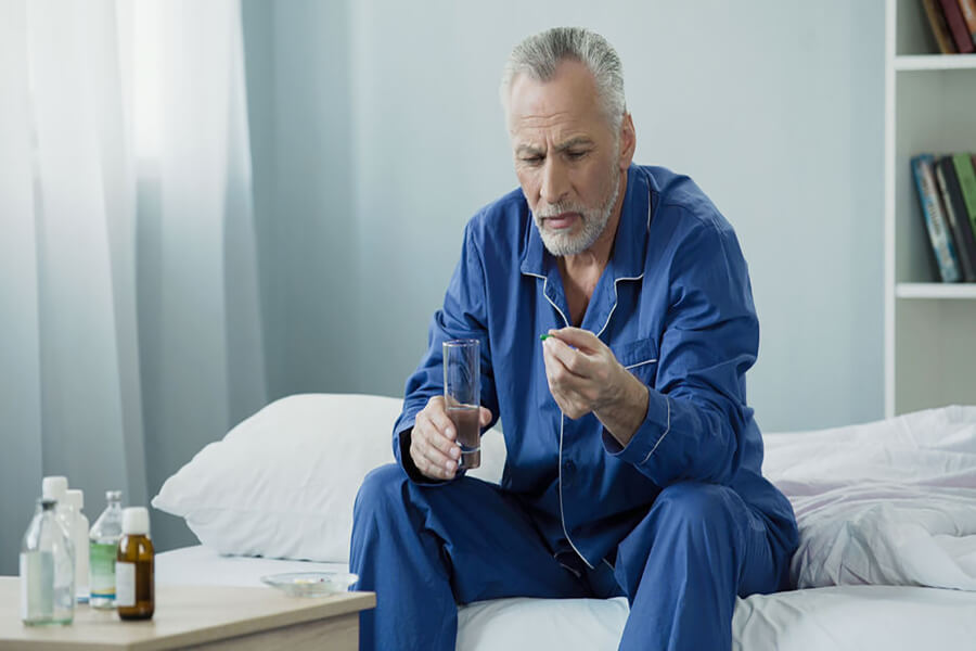 Older man taking pill in pajamas