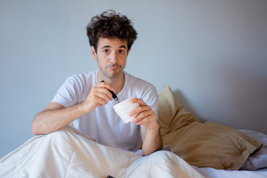 Man eating ice cream in bed