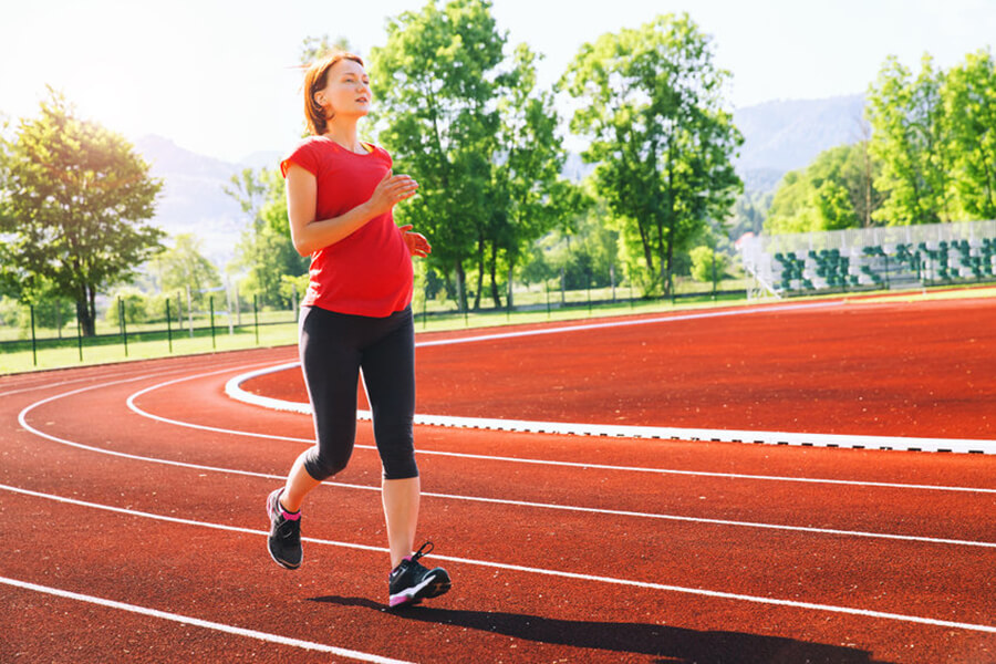 Pregnant woman running on track