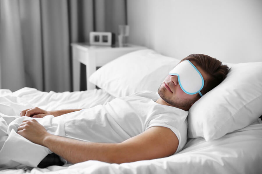 Male asleep in bed eye mask