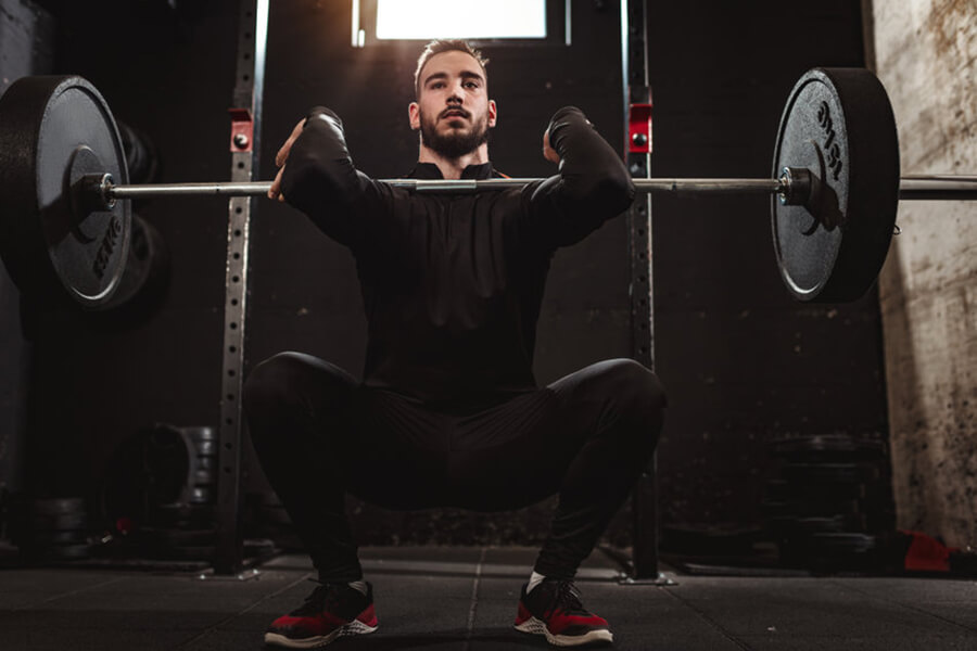 Male athlete performing squat with barbell