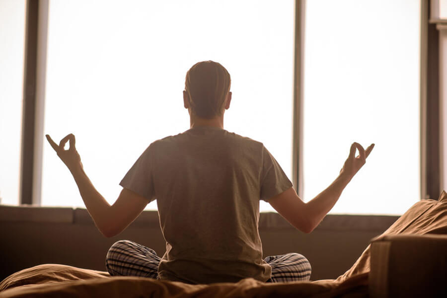 Male meditating in bed